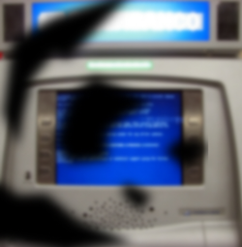An ATM as seen through the eyes of a person with diabetic retinopathy. The image is blurred and various sizes of black patches obscure vision.